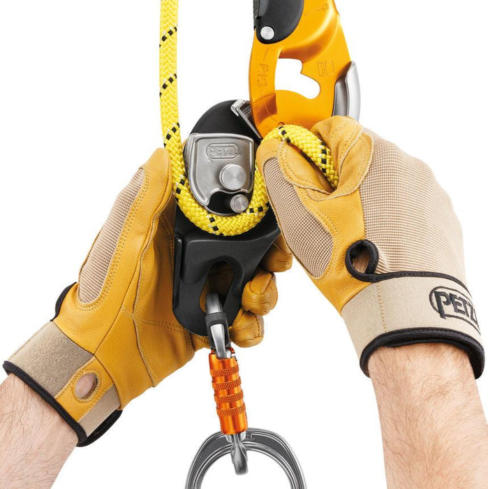 Professional wearing gloves installing a rope on the Petzl Rig descender. The safety gate on the moving side plate
allows the rope to be installed easily while the device remains connected to the
harness.