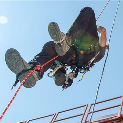 Rescue professional using the Harken Ninja Foot Ascender to climb a rope, with secure harnessing and climbing gear visible against a clear sky background.