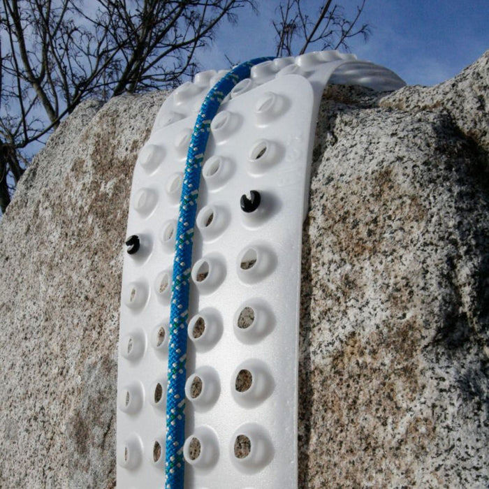 The SMC Flex Rope Protector wrapped over a rough rock edge, protecting a blue rope from abrasion and ensuring smooth rope movement during rigging.