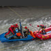 A group of rescue responders in red and blue life jackets collaborates on a boat and a car, demonstrating teamwork and safety at sea.