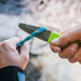 Hand model demonstrating Green Gear Aid Akua River Knife about to cut a blue cord 